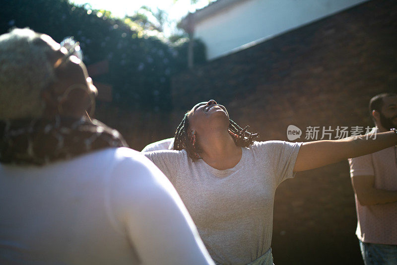 一群朋友/家人在花园里玩，女人在跳舞，抬头看